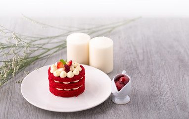 Red Velvet homemade cake decorated with cream with white plate on vintage wood table.