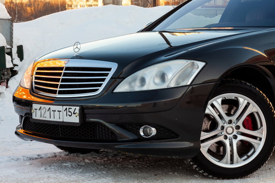 The front part of a black car of the executive business class of the brand Mercedes Benz, model amg on the street prepared for sale on a sunny winter day and with a brand sign on the hood.