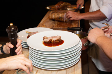 piece of pork cut by the chef on chopping board professional cook holding knife and cutting meat in restaurant