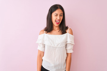 Beautiful chinese woman wearing white t-shirt standing over isolated pink background winking looking at the camera with sexy expression, cheerful and happy face.