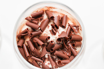 Layered trifle dessert with chocolate sponge cake, whipped cream and fruit jelly in serving glasses. - Image