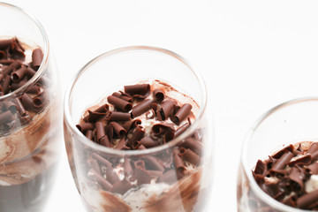 Layered trifle dessert with chocolate sponge cake, whipped cream and fruit jelly in serving glasses. - Image
