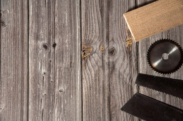 Equipment for manual sawing of wood. The border is made of two saw-hacksaw with small and large teeth, a Board and a disk on a wooden background. Free space for your text.
