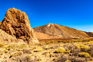 Highest Peak Behind A Large Lava Rock On A Sunny And Very Clear Day In El Teide National Park. April 13, 2019. Santa Cruz De Tenerife Spain Africa. Travel Tourism Street Photography.