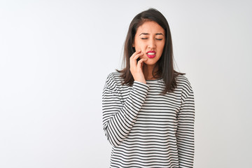Young beautiful chinese woman wearing striped t-shirt standing over isolated white background touching mouth with hand with painful expression because of toothache or dental illness on teeth