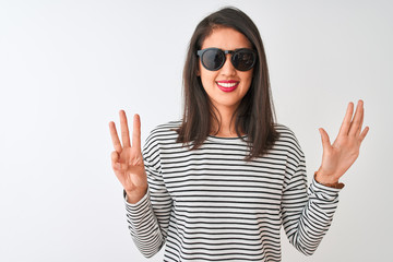 Chinese woman wearing striped t-shirt and sunglasses standing over isolated white background showing and pointing up with fingers number eight while smiling confident and happy.