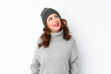 Young Russian woman with winter hat over isolated white background laughing and looking up