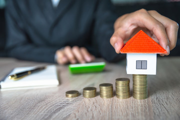 Business people are about to put their home on a pile of coins And have coins in a hemp bag,...