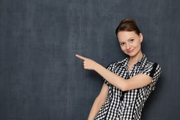 Portrait of happy satisfied young woman pointing at copy space