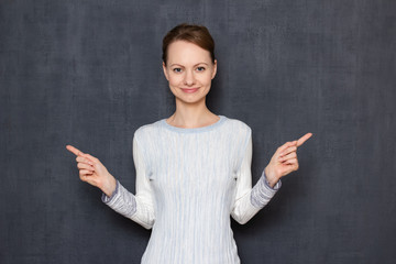 Portrait of happy girl pointing with index fingers to different sides