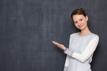 Portrait of happy young woman pointing with hand at copy space