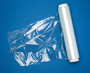 big roll of wound white transparent film for wrapping food, dark blue background