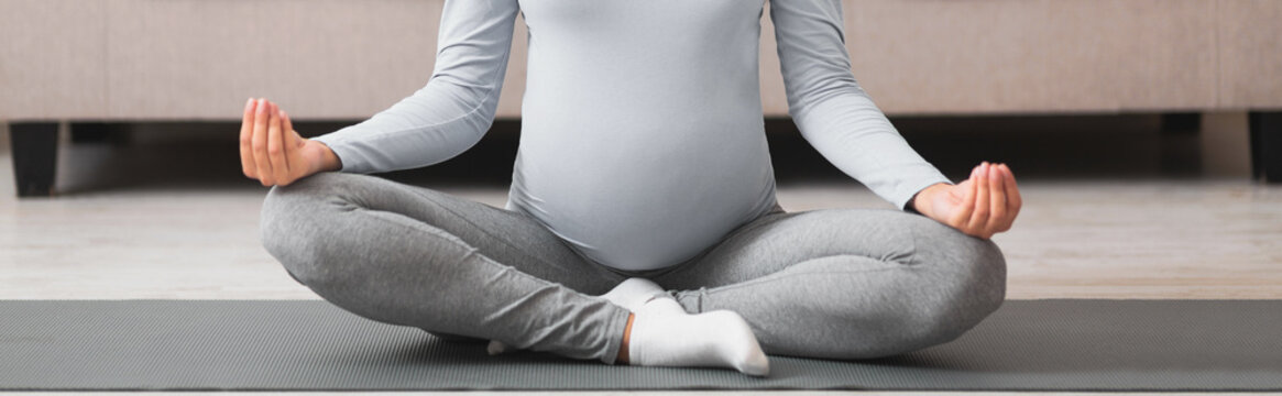 Cropped image of millennial expectant meditating on yoga mat