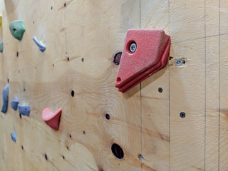 Closeup of red and colorful climbing pieces on a wall in a gym for climbing exercise both for leisure and professionally, practicing for extreme mountaineering