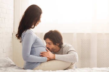 Naklejka na ściany i meble Future dad tenderly kissing belly of his pregnant wife