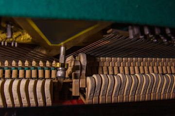 Close up of old broken dusty piano from the inside. Hammers in abandoned piano striking strings....