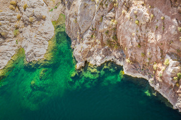 Aerial image looking down on the clear green waters of Lake Meade with the rocky shoreline.