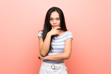 Teenager asian girl over isolated pink background thinking