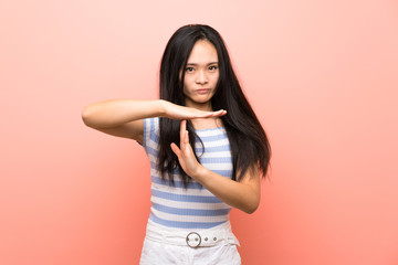 Teenager asian girl over isolated pink background making time out gesture