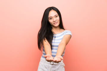 Obraz premium Teenager asian girl over isolated pink background holding copyspace imaginary on the palm to insert an ad