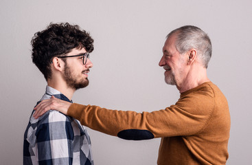 Portrait of a cheerful senior father and young son in a studio.