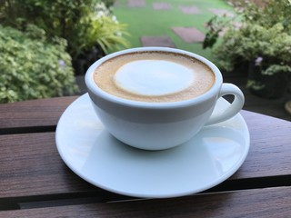 cup of hot coffee on wooden table in garden