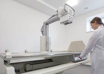 Female doctor preparing X-ray equipment for making roentgenogram for patient