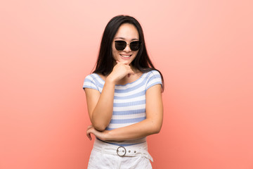 Fototapeta premium Teenager asian girl over isolated pink background with glasses and smiling