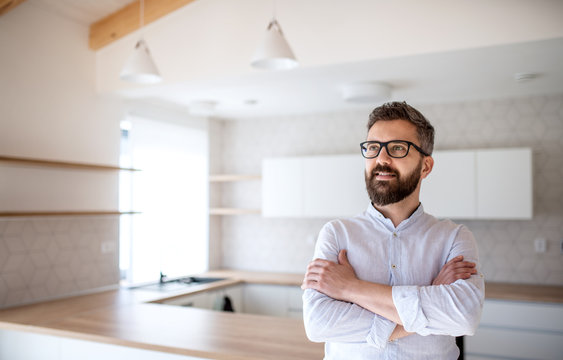 Mature man standing in house, moving in new home concept.