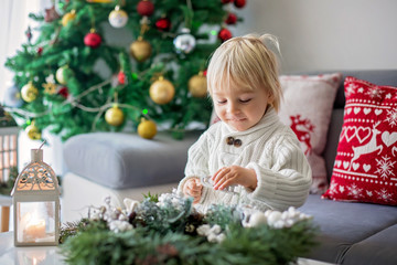 Little cute blonde toddler boy, making advent wreath at home