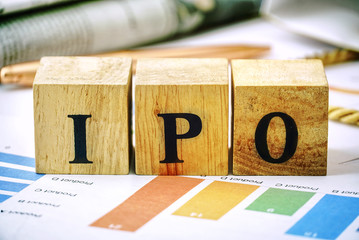 Text "IPO" on wood cube lay on chart candle document paper , stock investment concept.