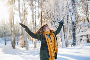 A portrait of young woman standing outdoors in snowy winter forest.