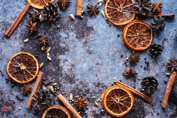 Fototapeta na wymiar Still life with a set for mulled wine. Dried orange, cinnamon sticks, pink pepper, cardamom, anise, cloves on a blue background. The view from the top