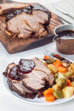 Pork shoulder in honey parmesan and soy souse, prepared in slow cooker or crockpot, served with carrot, potato and brussel cabbage, on white plate, vertical