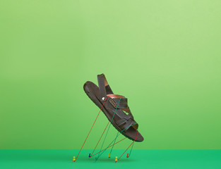flying leather man's sandal, held by threads on a green background for banner.