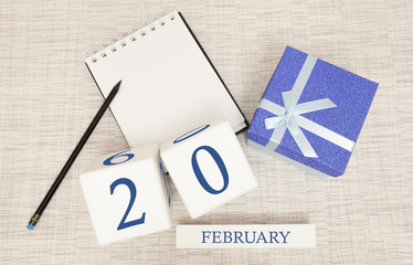 Calendar with trendy blue text and numbers for February 20 and a gift in a box.