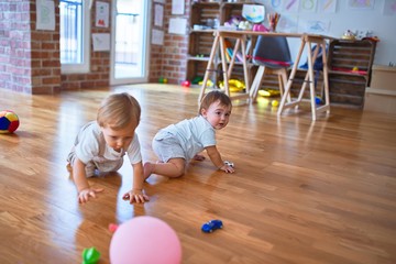 Fototapeta premium Beautiful toddlers playing around lots of toys at kindergarten