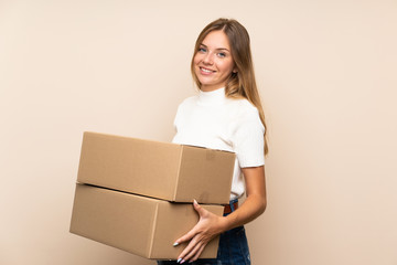 Young blonde woman over isolated background holding a box to move it to another site