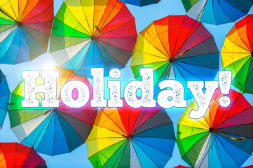 Holiday! Text on the background of colorful multi colored umbrellas. Street Decorations and Celebration.