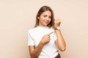 Young blonde woman over isolated background showing the hand watch