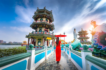 Obraz premium Asian Woman Wearing Cheongsam Traditional Red Dress standing on bridge at Wuliting pavilion,Kaohsiung,Taiwan.