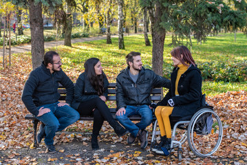 Young disabled woman in a wheelchair with friends in a park