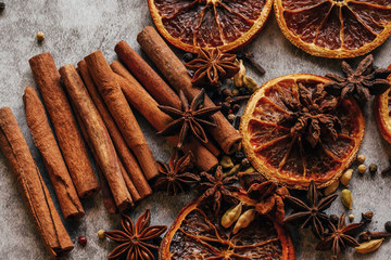 Christmas spice background. Cinnamon, dried oranges and anise on a grey background.