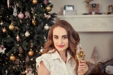 A beautiful young woman sits by a Christmas tree and opens gifts. Christmas. New Year. Cozy.