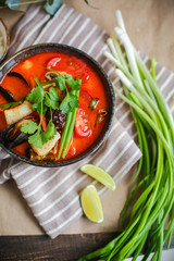 Bowl of stir fried udon noodles garnished with black sesame seeds and fresh mint with green chopsticks