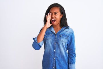 Beautiful young african american woman wearing denim jacket over isolated background shouting and screaming loud to side with hand on mouth. Communication concept.