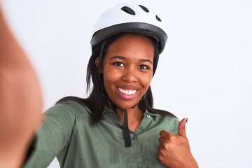Young african american woman wearing bike helmet taking a selfie over isolated background happy with big smile doing ok sign, thumb up with fingers, excellent sign