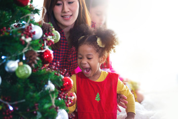 Fototapeta na wymiar Asian little girl and mother enjoying Christmas tree decoration, Christmas concept