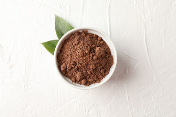 Bowl with cocoa powder and leaves on white background, space for text