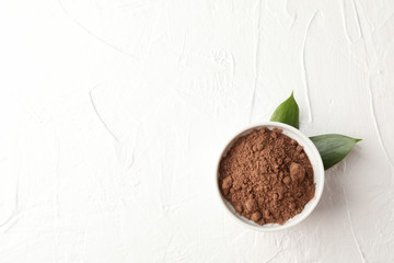 Bowl with cocoa powder and leaves on white background, space for text
